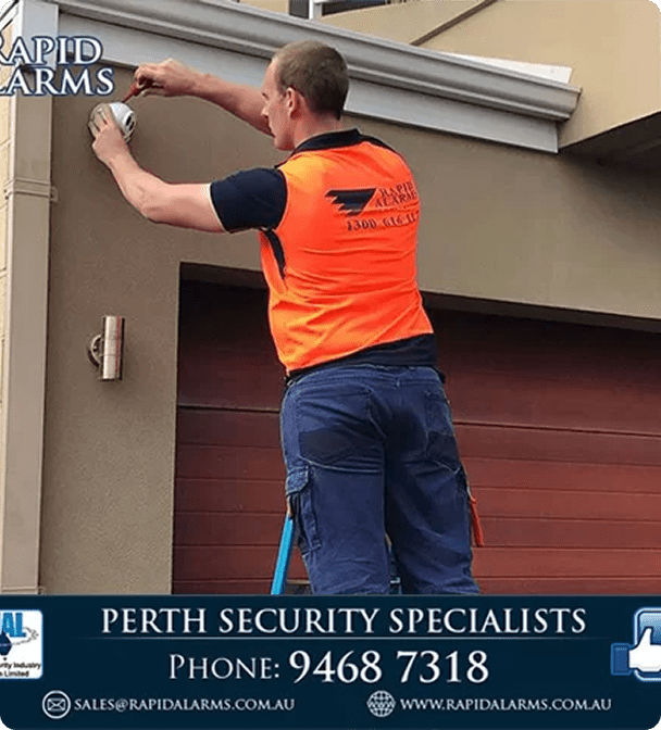 image (29) Technician installing CCTV camera on residential property in Perth, wearing safety vest, demonstrating professional security installation services by Rapid Alarms.